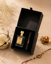A black gift box opened to reveal a clear perfume bottle named Velvet Vanille with a gold cap and a black cosmetic stick with gold lettering, styled on a beige surface with dried flowers, a small bowl, and a lit gold candle.